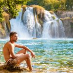 KRKA waterfalls Croatia during summer, young men sunbathing at the waterfalls of krka